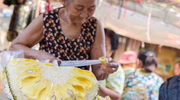 Vrouw snijdt jackfruit op Phsar Kranat Market
